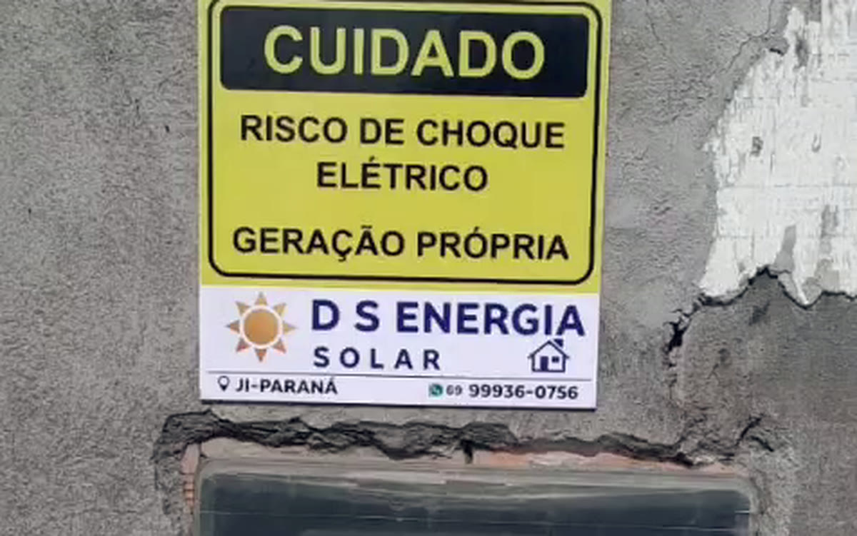 Placa de aviso da D S Energia Solar sobre o padrão de energia, indicando geração própria.