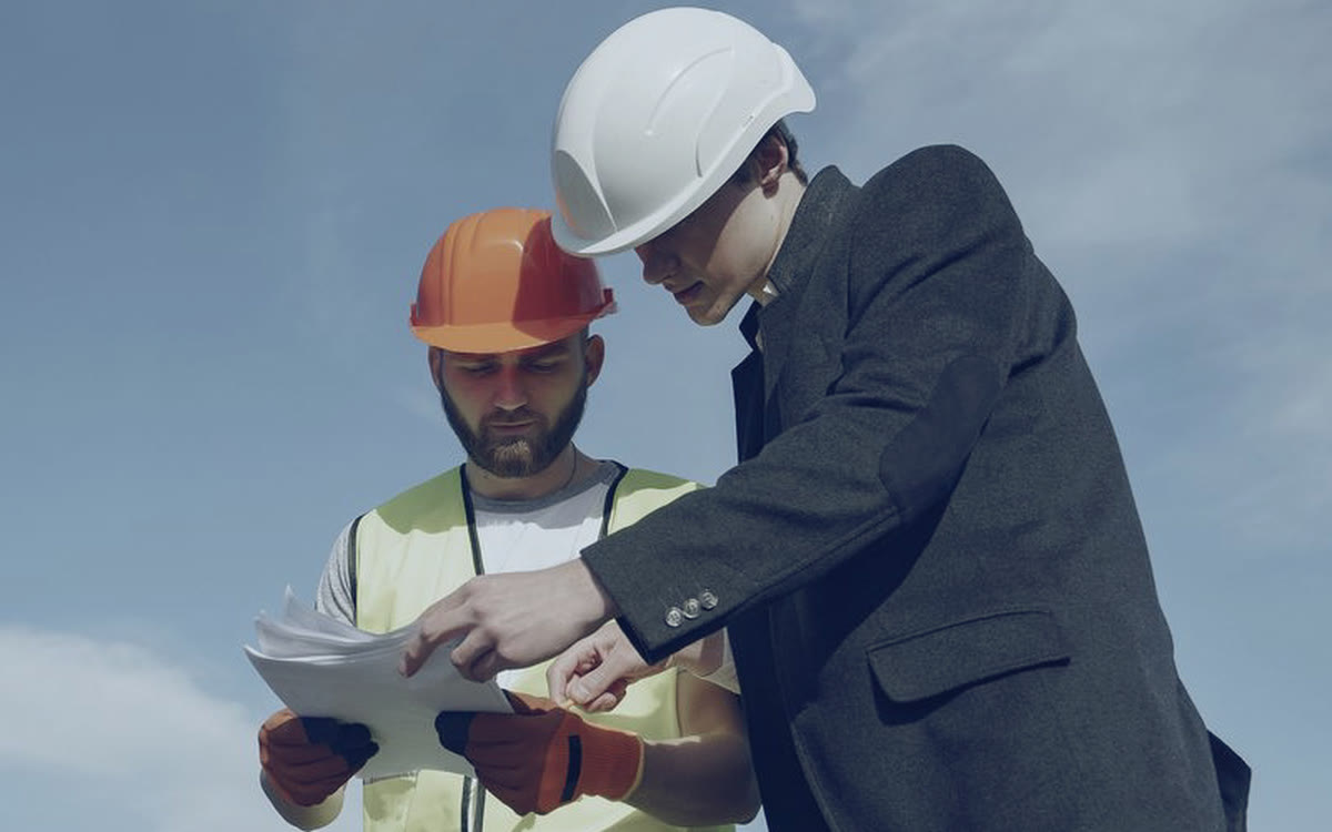 Dois profissionais conferindo juntos o projeto impresso do sistema de energia solar.