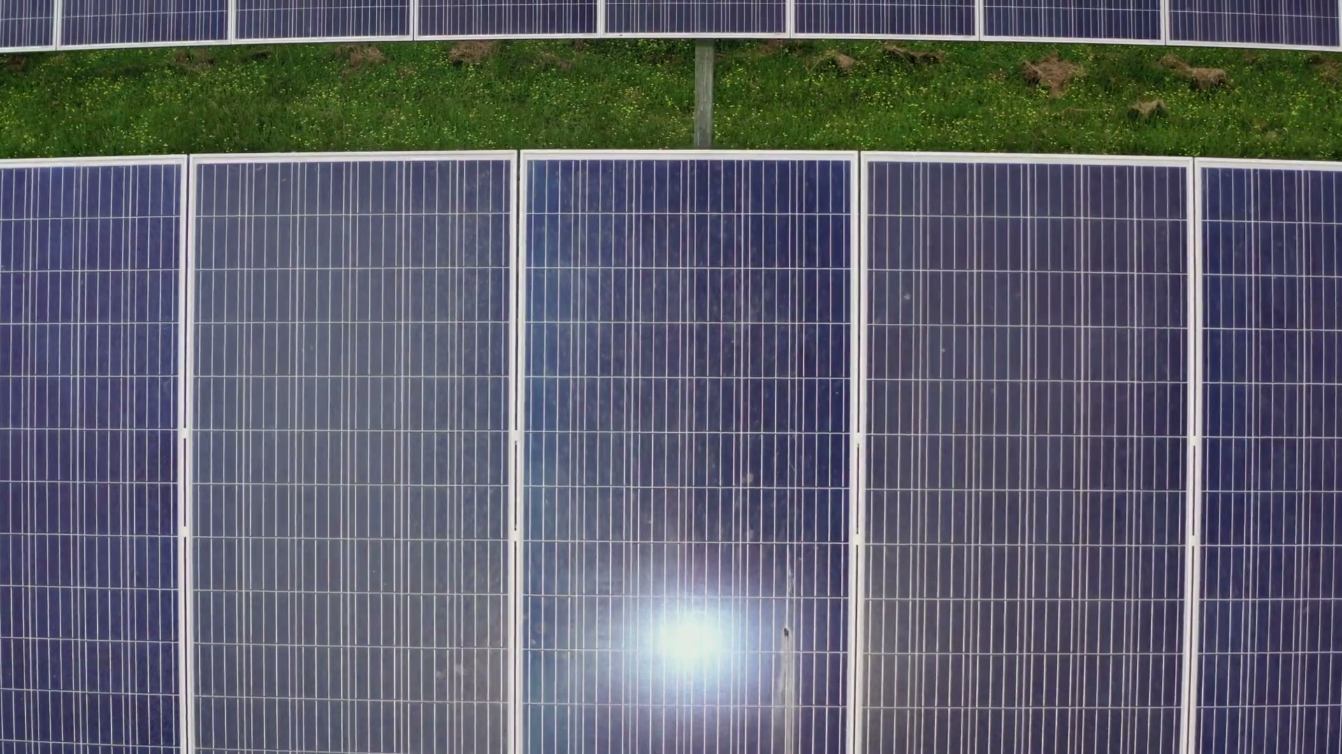 Reflexo do sol sobre a superfície de um painel solar, visto de cima.