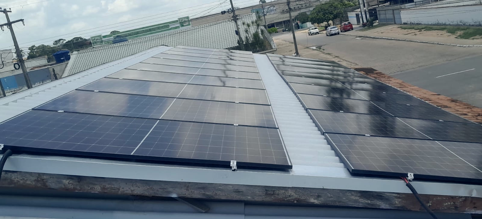 Sistema de energia solar completo instalado sobre o telhado de um comércio em Ji-Paraná, visto de cima.