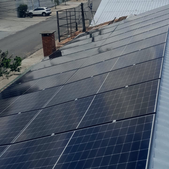 Fileiras de painéis solares no telhado, com as casas da cidade ao fundo.